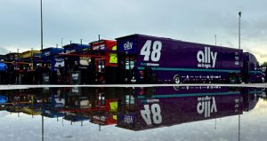 Haulers at Talladega are lined up with a massive puddle from rain in the foreground.