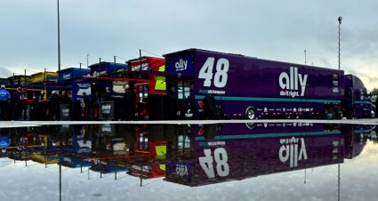 Haulers at Talladega are lined up with a massive puddle from rain in the foreground.